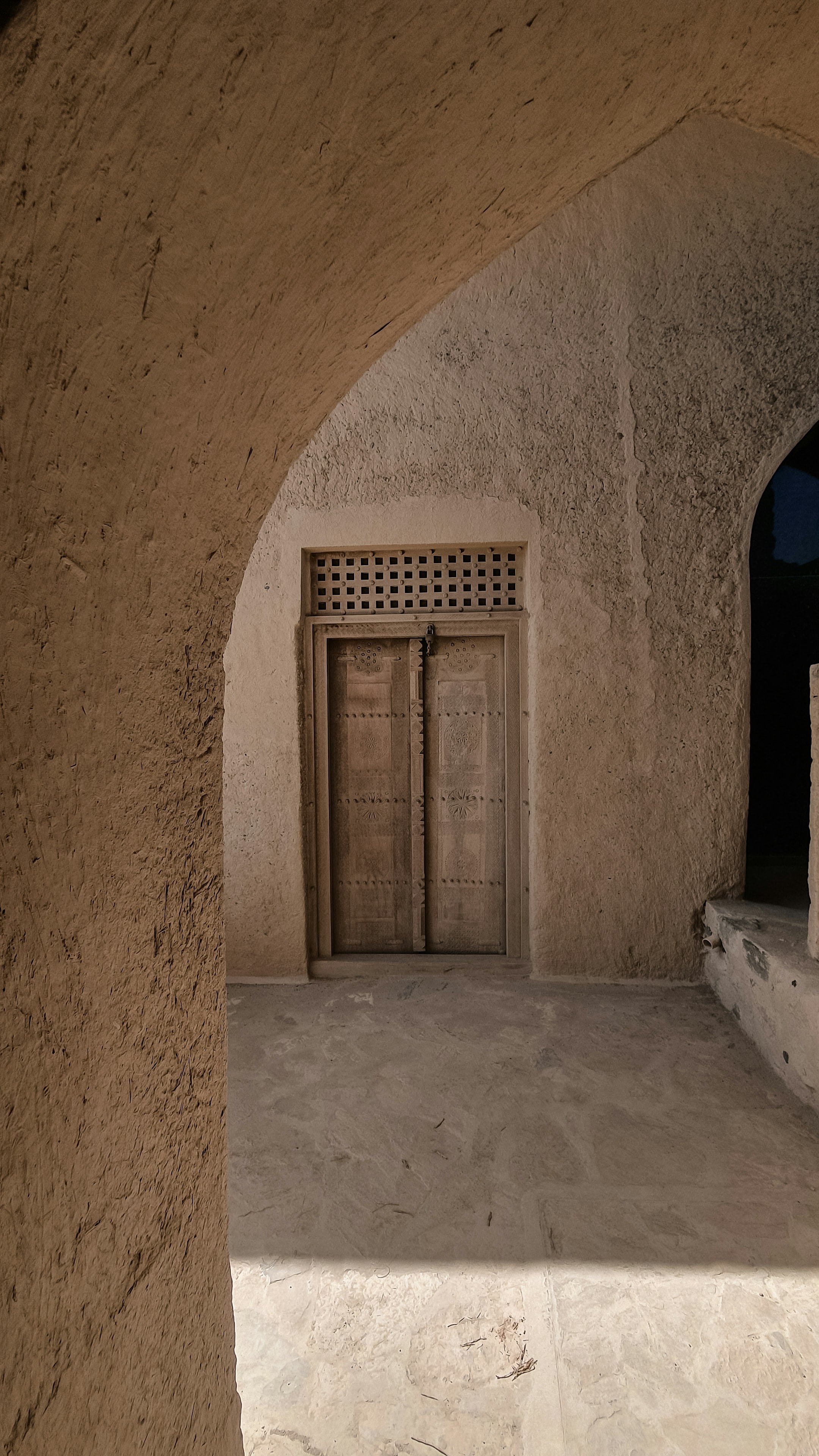 A carved wooden door beneath a sandstone arch in a traditional fort
